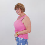 Woman wearing a pink top and blue floral pants against a white background