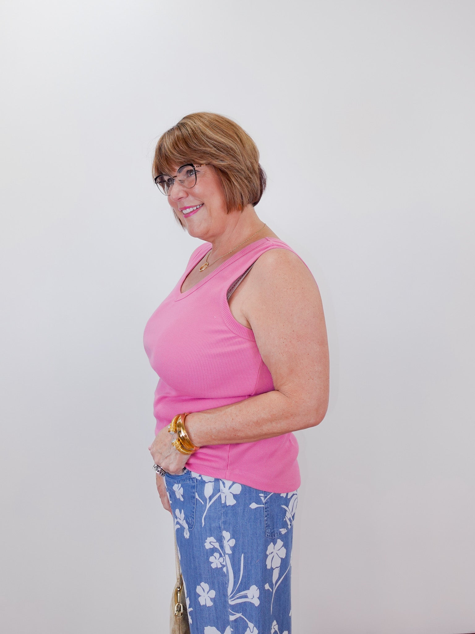 Woman wearing a pink top and blue floral pants against a white background
