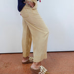 Person wearing beige pants and brown shoes on a plain background