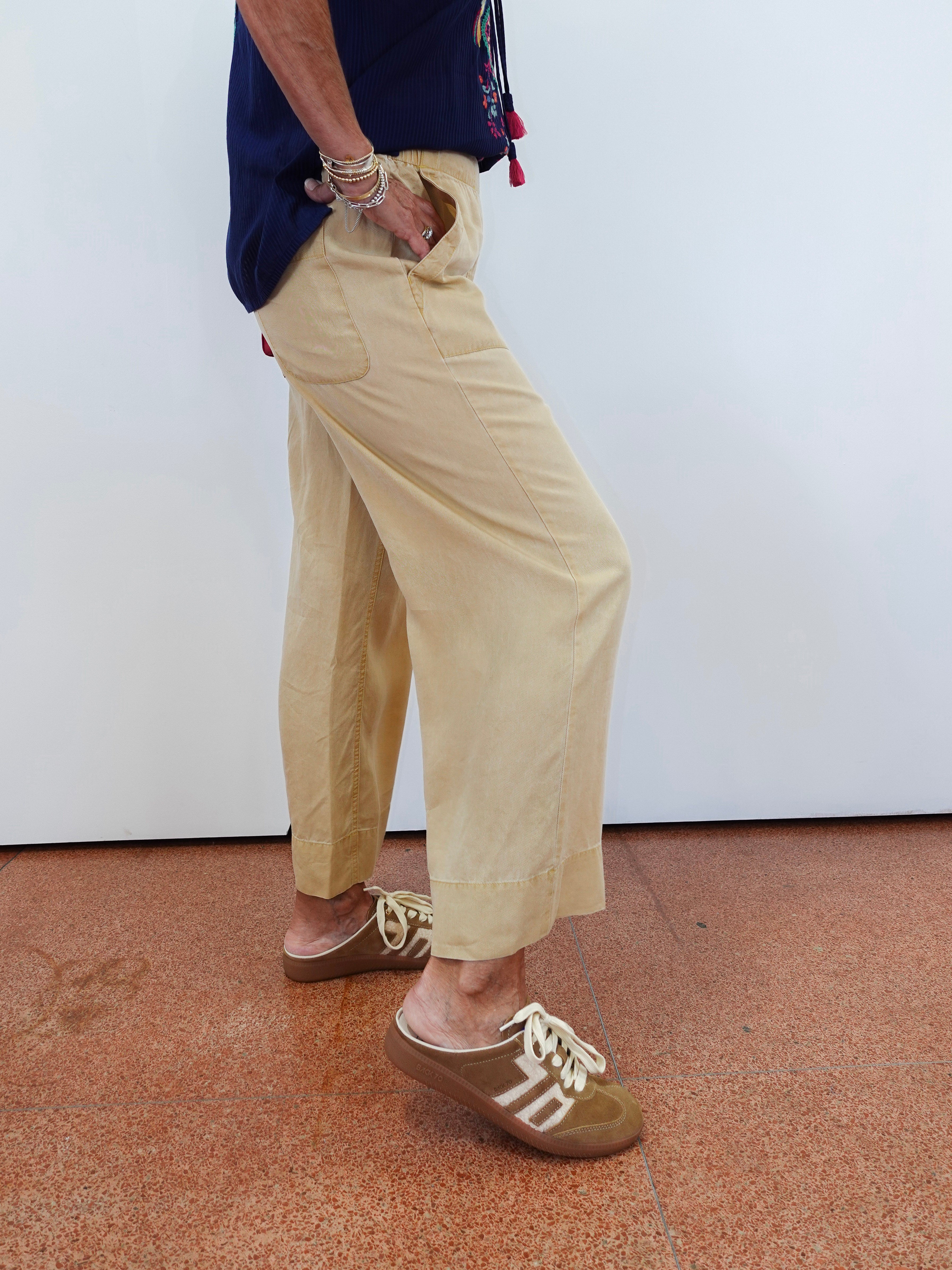 Person wearing beige pants and brown shoes on a plain background