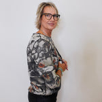 Woman wearing a patterned jacket and glasses against a plain background