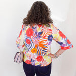 Person wearing a colorful floral blouse with a plain background