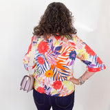 Person wearing a colorful floral blouse with a plain background