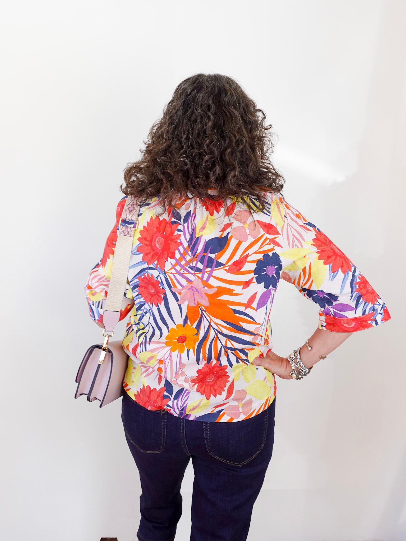 Person wearing a colorful floral blouse with a plain background