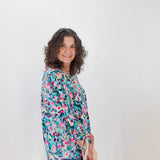 Woman wearing a colorful floral blouse against a white background