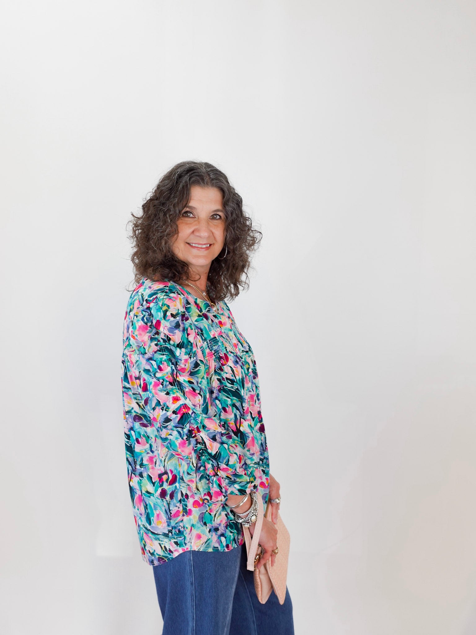 Woman wearing a colorful floral blouse against a white background