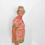 Woman wearing a colorful patterned shirt against a white background