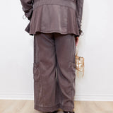 Person wearing a gray outfit with wide-leg pants against a white wall.