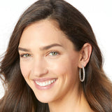 Close-up of a woman wearing pearl earrings with a plain background
