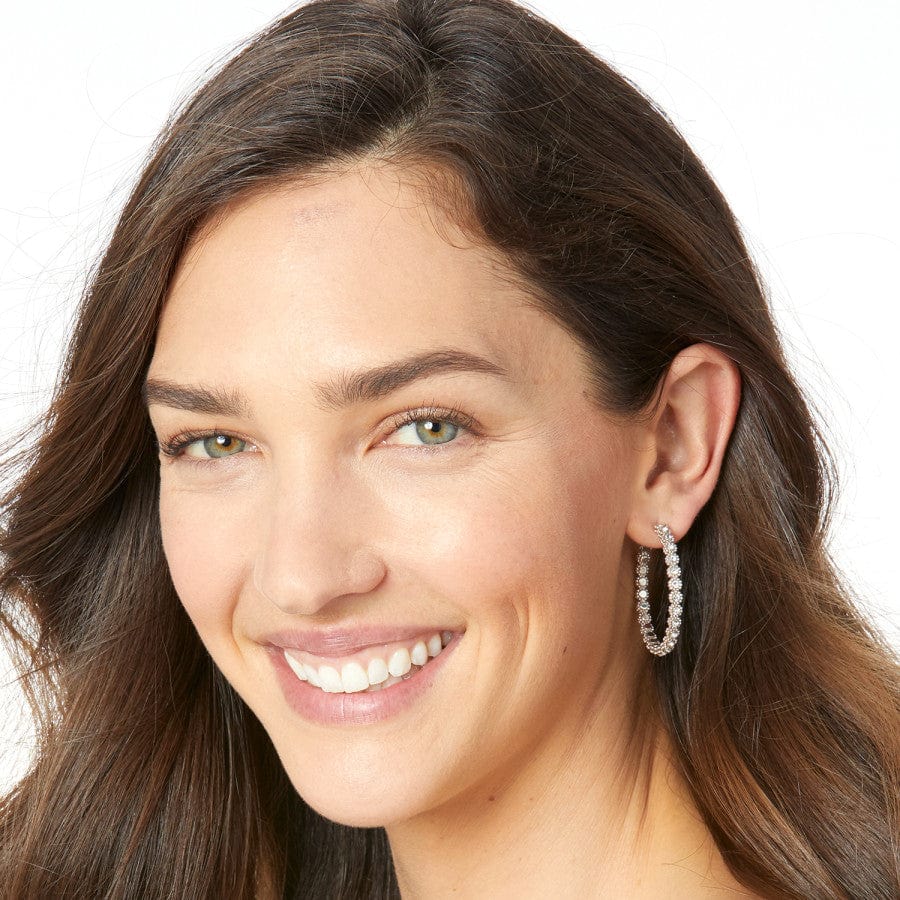 Close-up of a woman wearing pearl earrings with a plain background