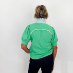 Person wearing a green shirt with a white stripe on a plain background