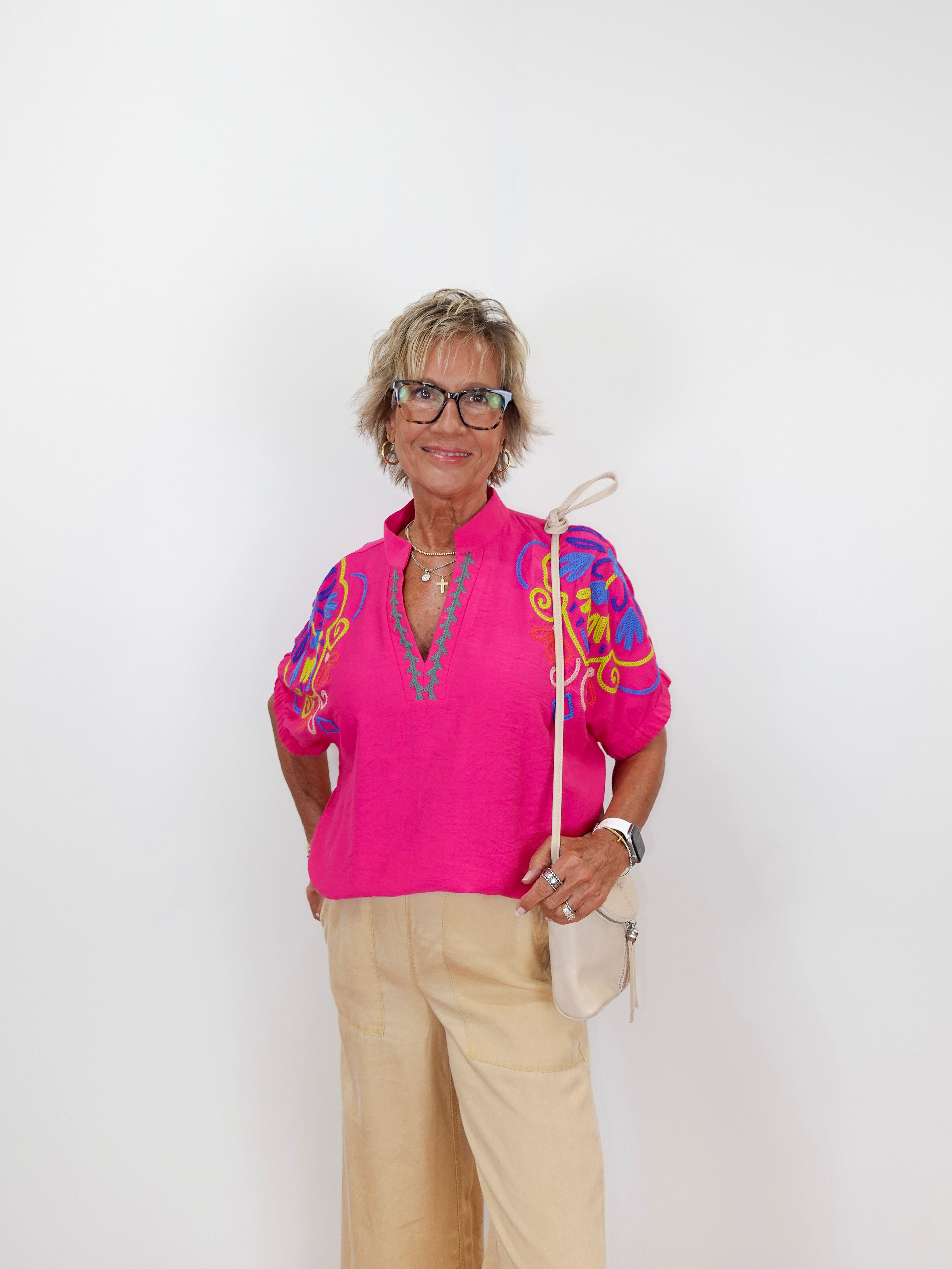 Woman wearing a bright pink blouse with colorful sleeves on a white background