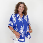 Woman wearing a blue and white patterned blouse against a white background