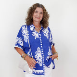Woman wearing a blue and white patterned blouse against a white background
