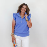 Woman wearing a blue top and white pants against a white background