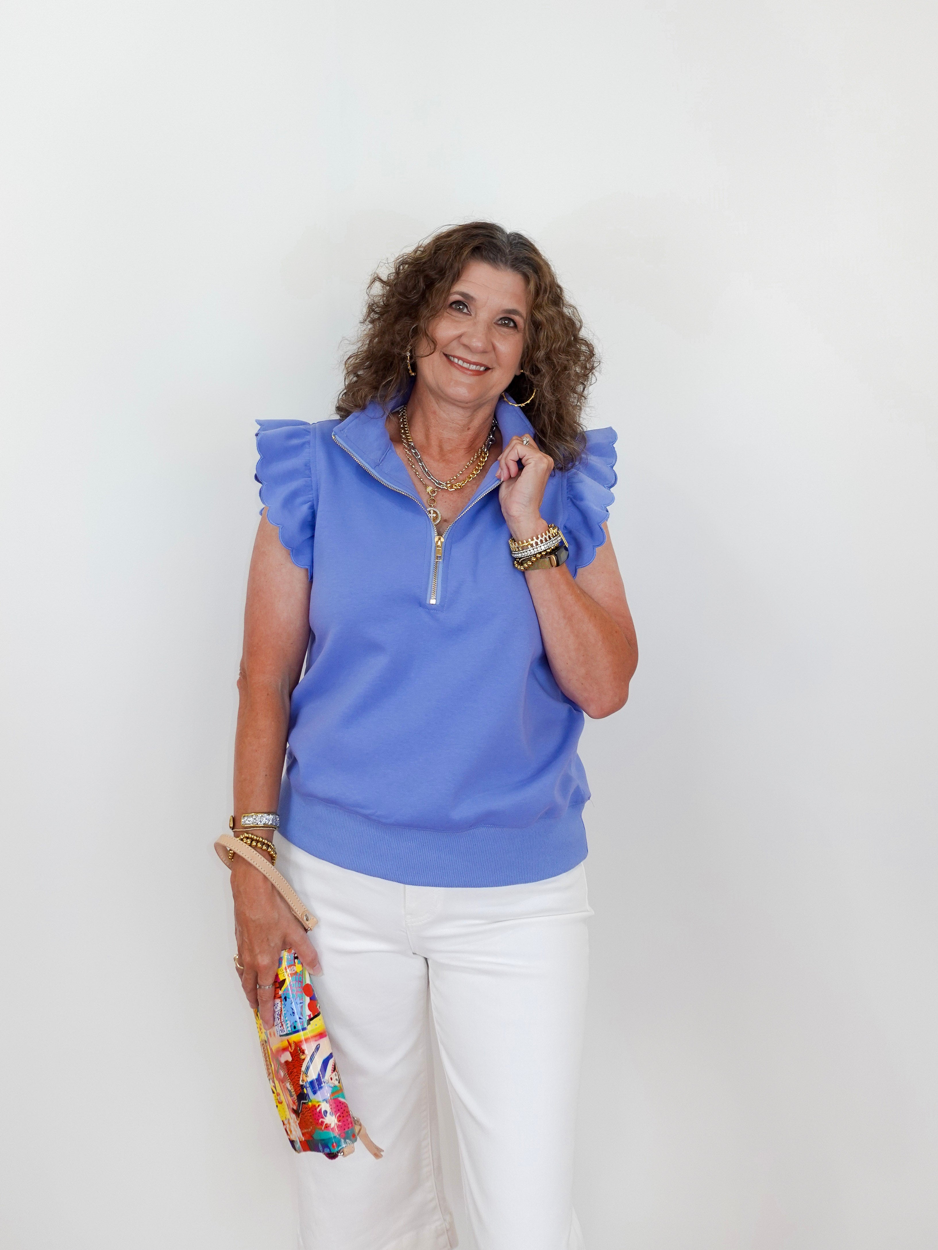 Woman wearing a blue top and white pants against a white background