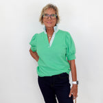 Woman wearing a green shirt and black pants against a white background