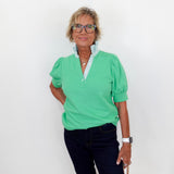 Woman wearing a green shirt and black pants against a white background