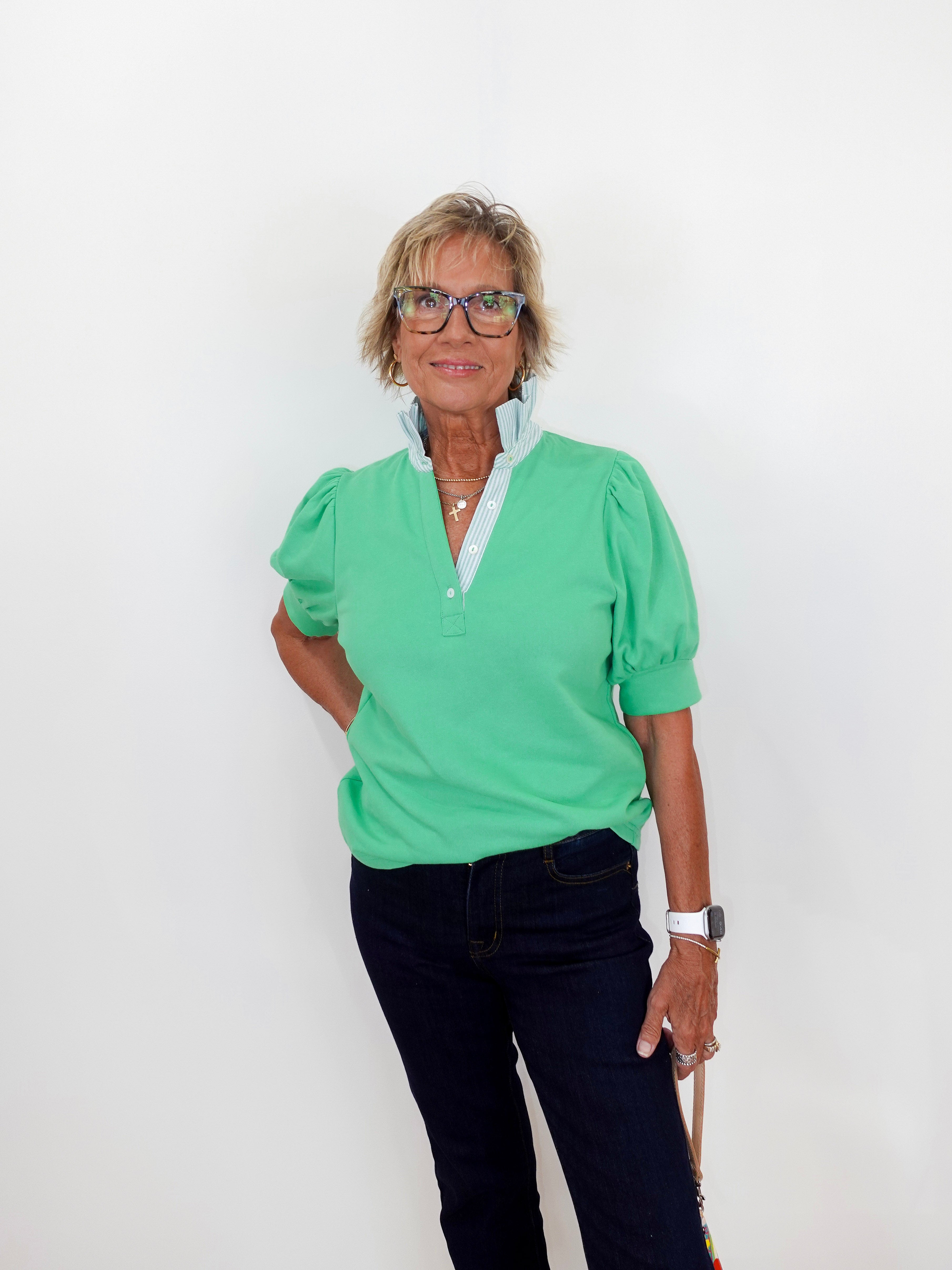 Woman wearing a green shirt and black pants against a white background