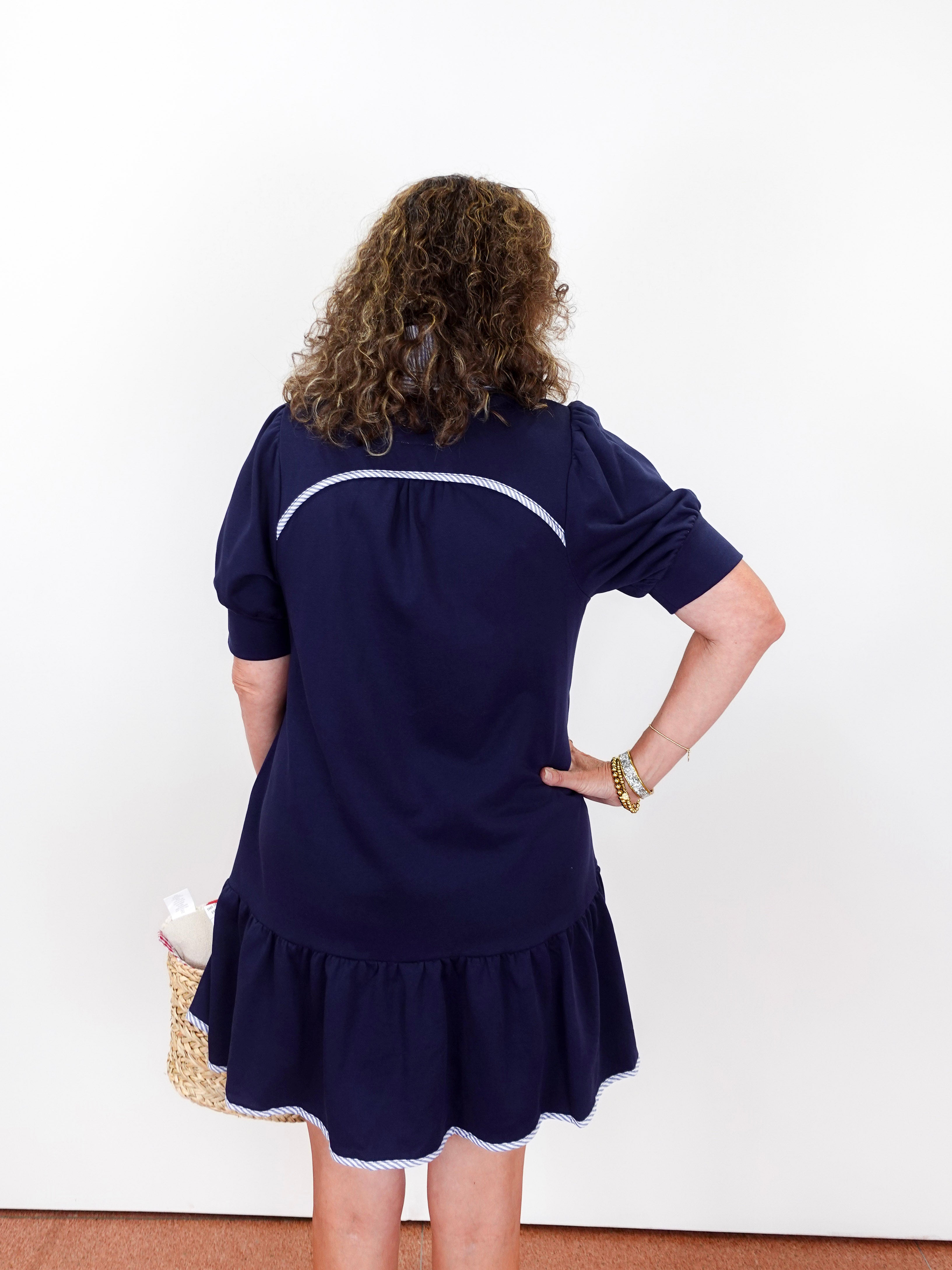 Woman wearing a navy dress with white trim against a white background