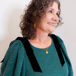 Woman wearing a green dress with black shoulder accents against a plain background