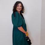 Woman wearing a green dress against a white wall