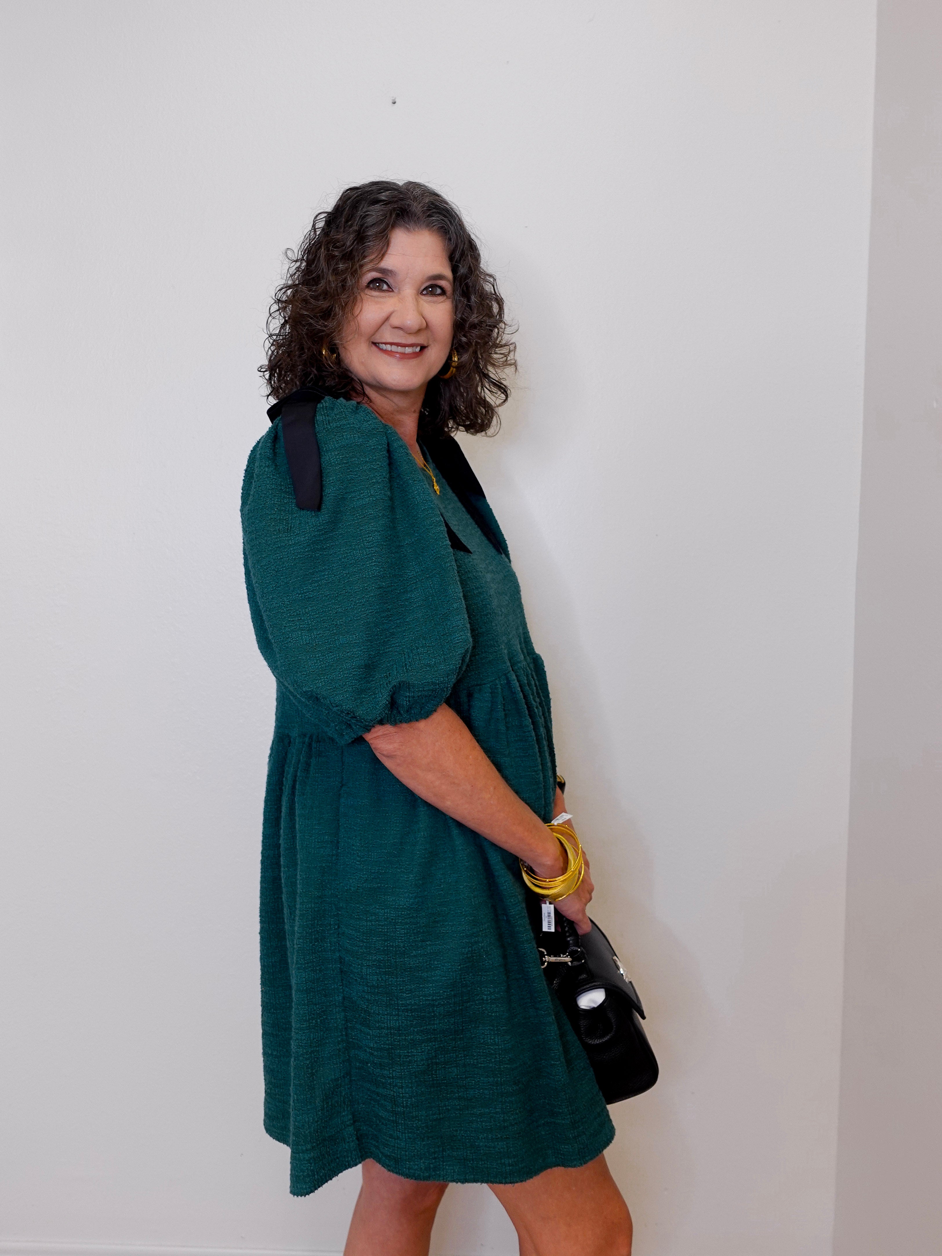 Woman wearing a green dress against a white wall