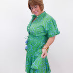 Woman wearing a green patterned dress against a white background