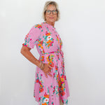 Woman wearing a pink floral dress against a white background
