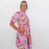 Woman wearing a pink floral dress against a white background