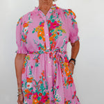 Woman wearing a pink floral dress against a white background