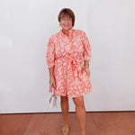 Woman wearing a pink floral dress against a white background