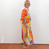 Person wearing a colorful dress standing against a white wall.