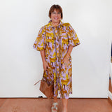 Woman wearing a patterned dress with a white wall background
