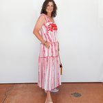 Woman wearing a red and white patterned dress standing against a plain background