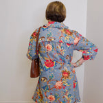 Person wearing a floral dress with a plain white wall background