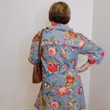 Person wearing a floral dress with a plain white wall background