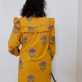 Person wearing a yellow dress with floral patterns against a white background