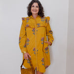 Woman wearing a yellow floral dress against a white wall