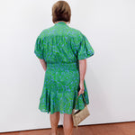 Woman wearing a green dress with a white wall background