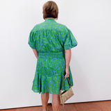 Woman wearing a green dress with a white wall background