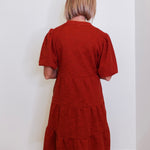 Woman wearing an uncle frank tiered knit dress against a white background. 