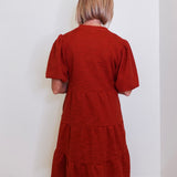 Woman wearing an uncle frank tiered knit dress against a white background. 