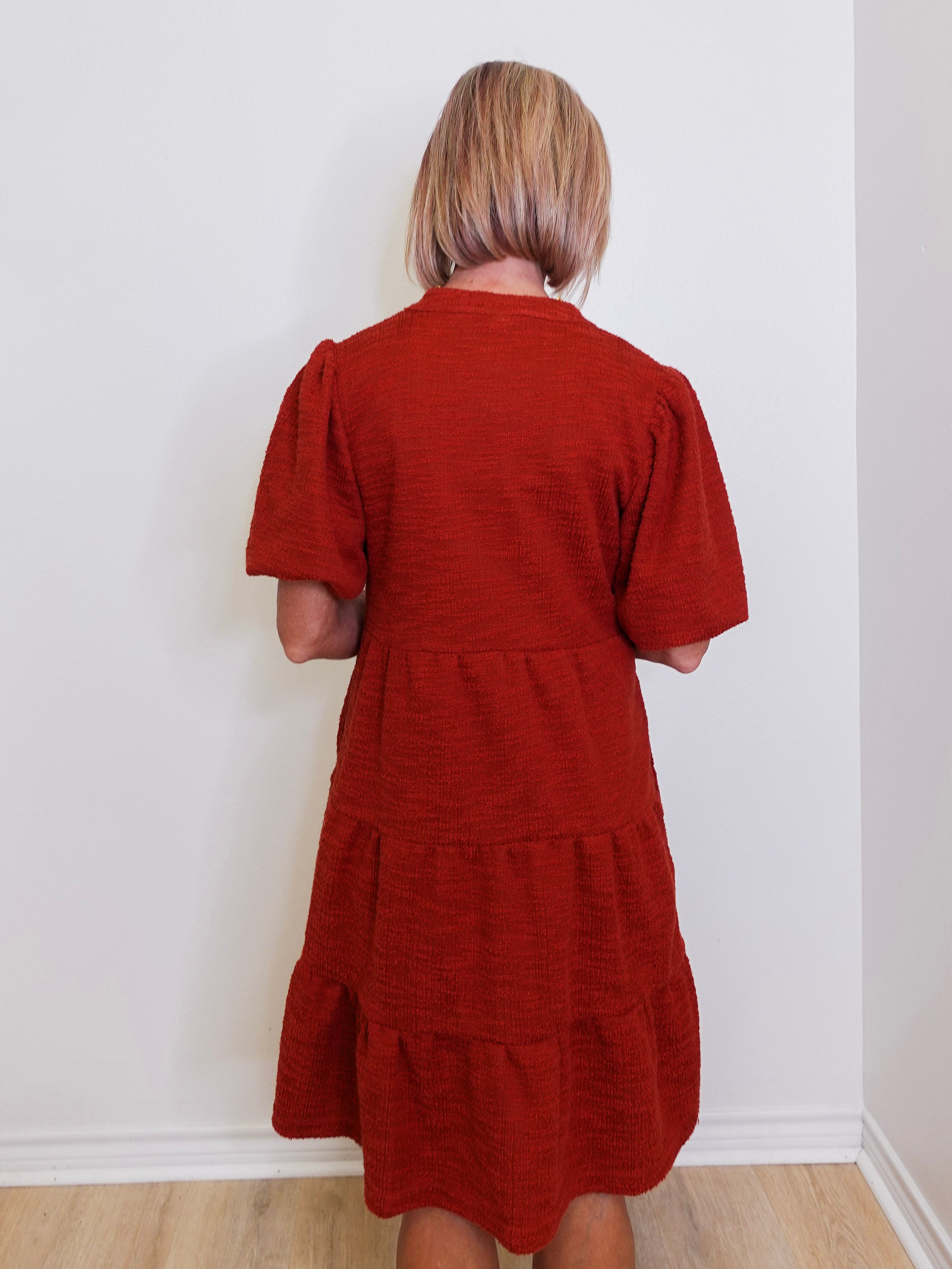 Woman wearing an uncle frank tiered knit dress against a white background. 