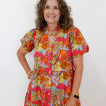Woman wearing a colorful floral dress against a white background