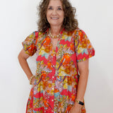 Woman wearing a colorful floral dress against a white background
