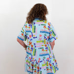 Person wearing a colorful patterned dress on a plain background