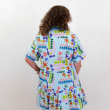 Person wearing a colorful patterned dress on a plain background