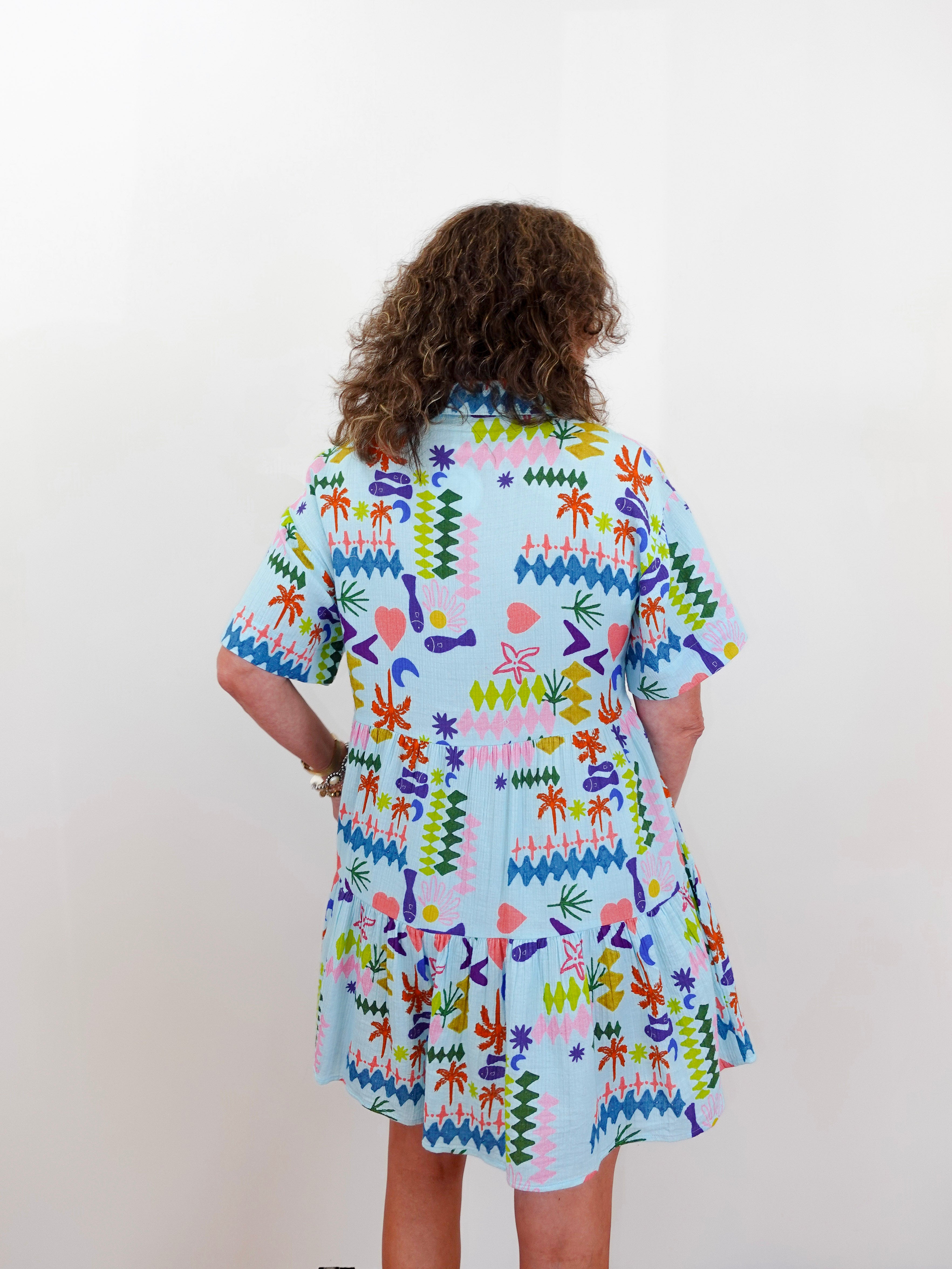 Person wearing a colorful patterned dress on a plain background