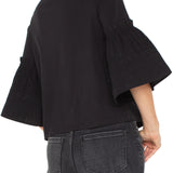 Person wearing a black blouse with ruffled sleeves and gray jeans on a white background